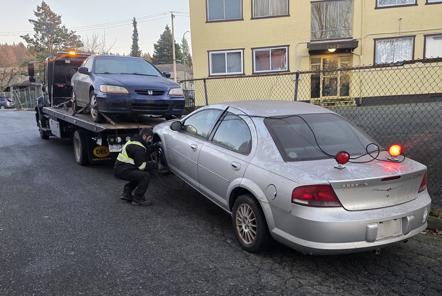 Silver sedan secured beside a flatbed truck