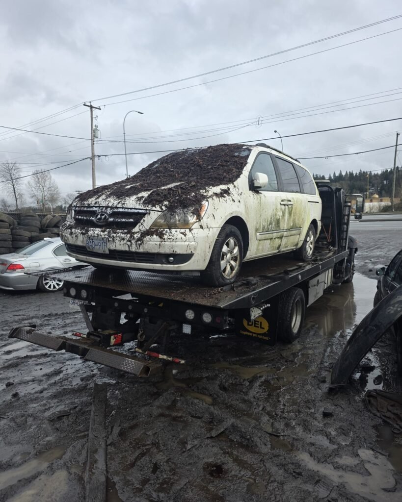 Damaged white car secured on a flatbed tow truck