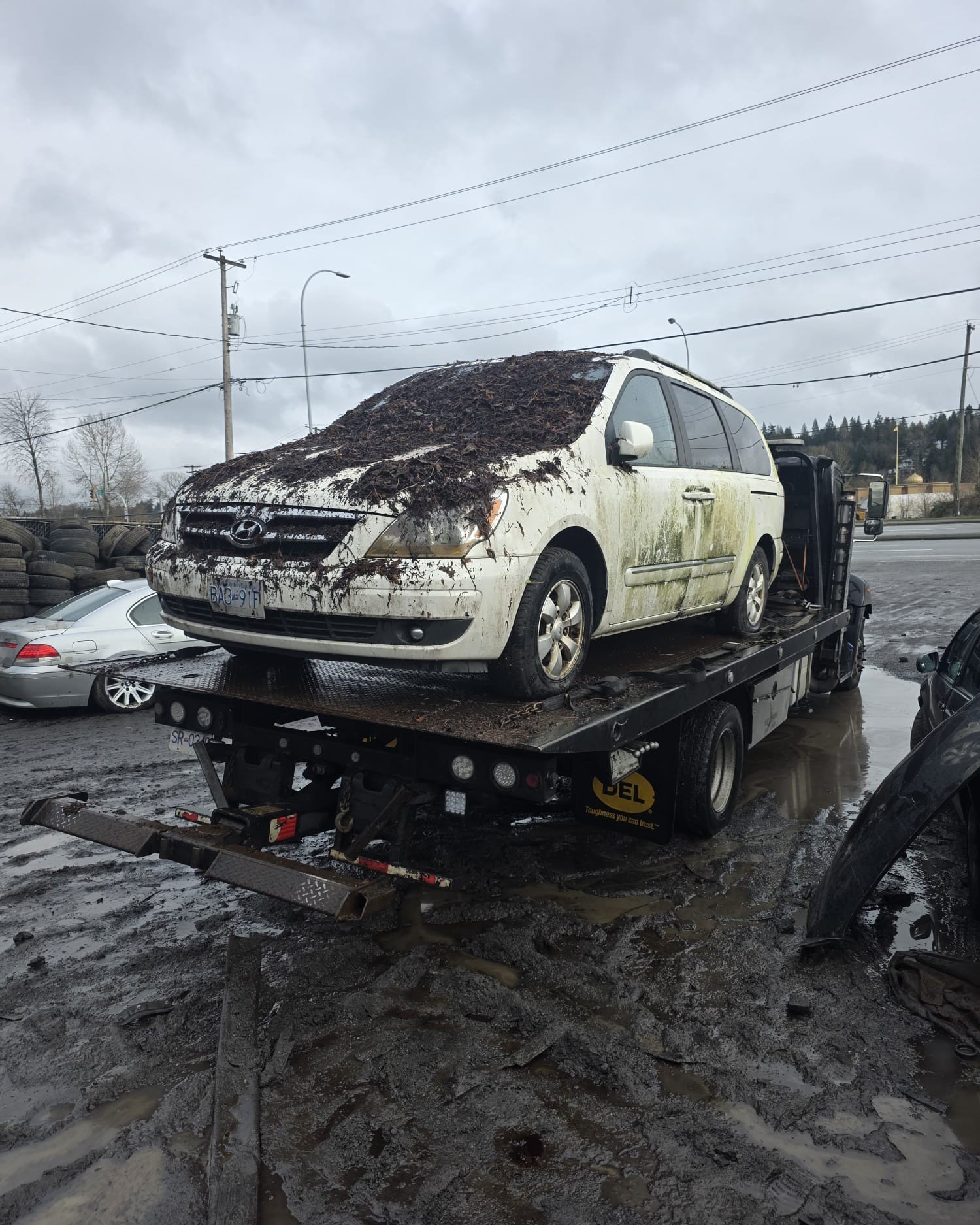 Damaged white car secured on a flatbed tow truck